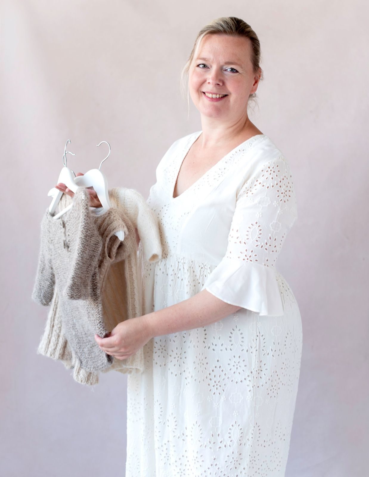 Brenda Olie in her studio holding knitted baby outfits